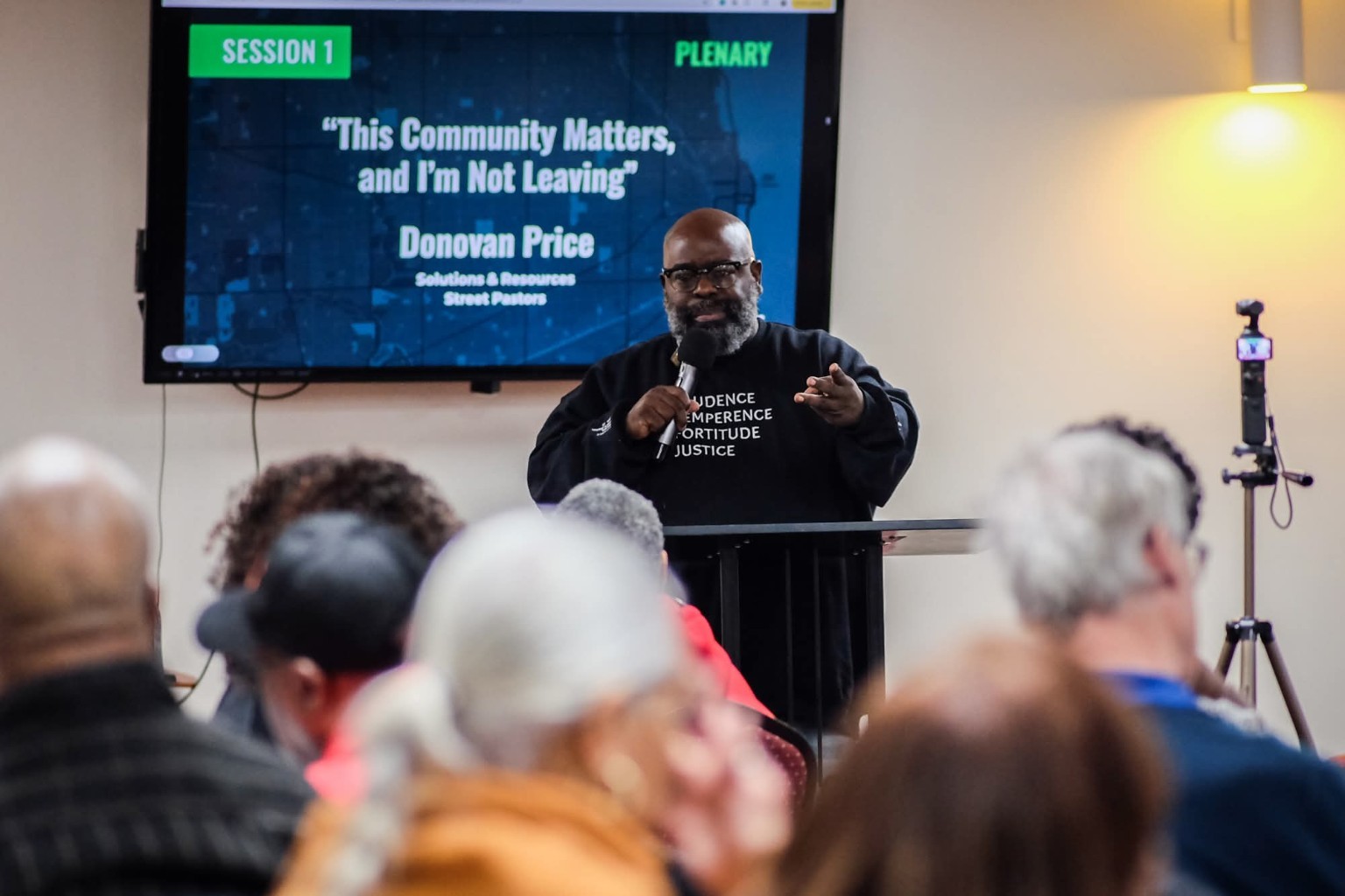 A speaking photograph supplied in the SnR media kit, showing a presentation to an audience.